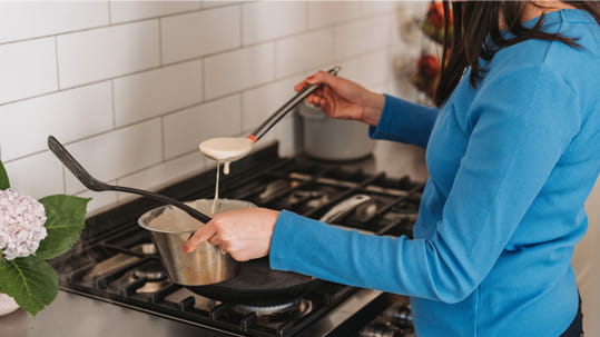 woman cooking pancakes on gas hob