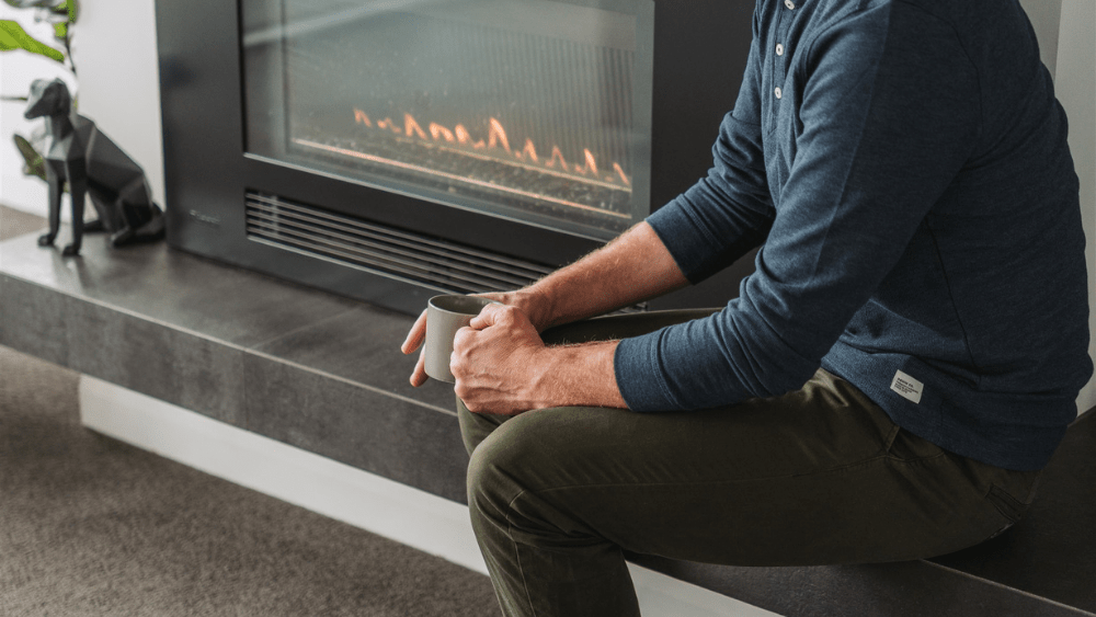 Man sitting next to gas fireplace