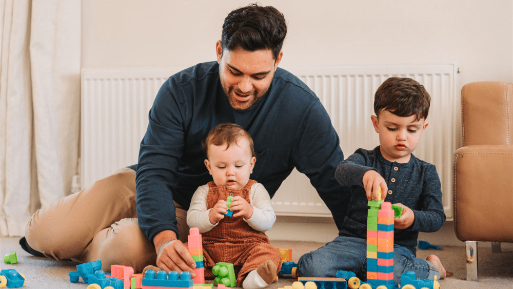 Dad playing with kids in front of natural gas radiator.
