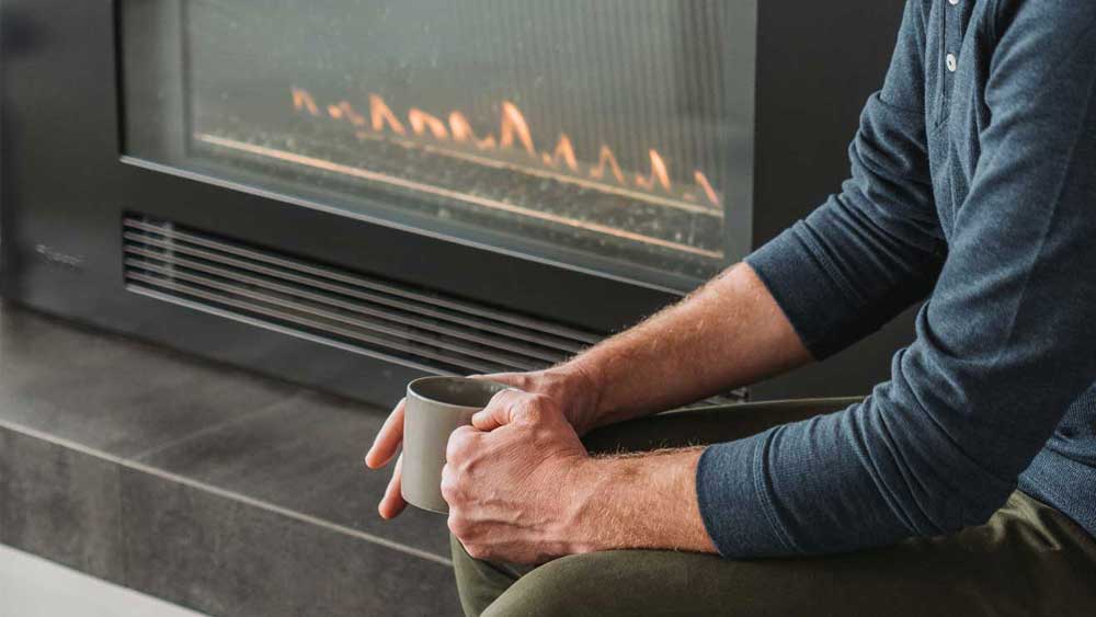 man holding mug in front of gas fire