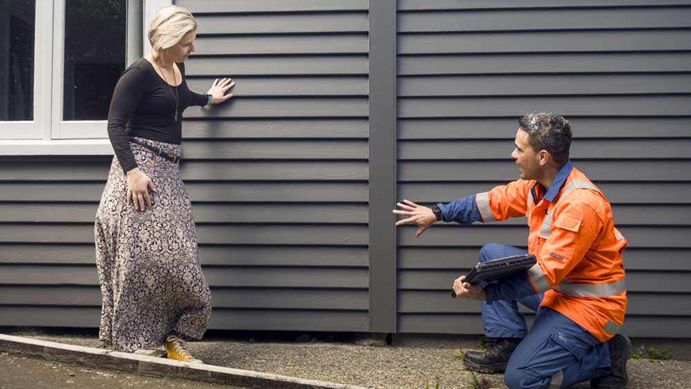 man and woman talking next to house