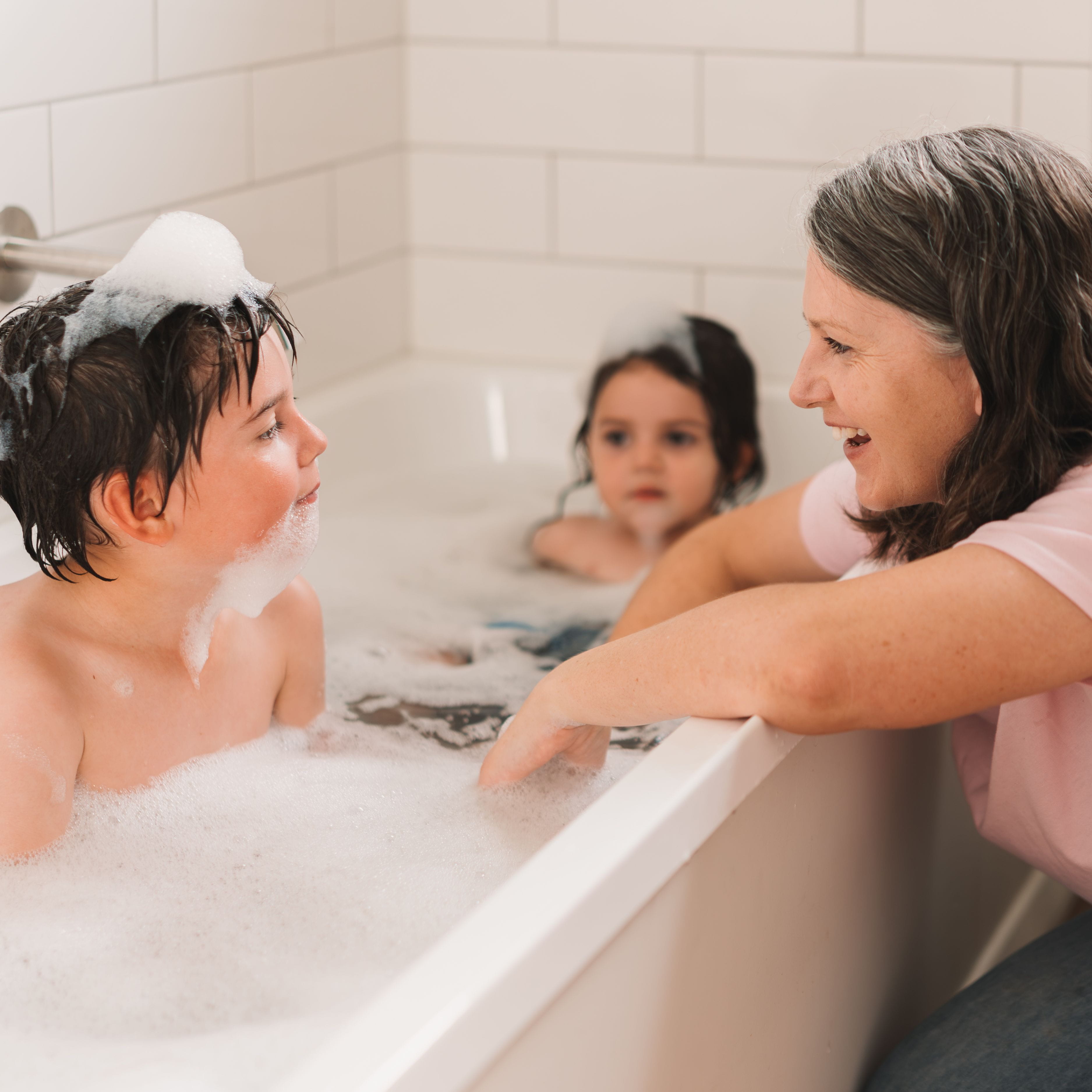 Mother baths kids in bath heated by gas hot water.