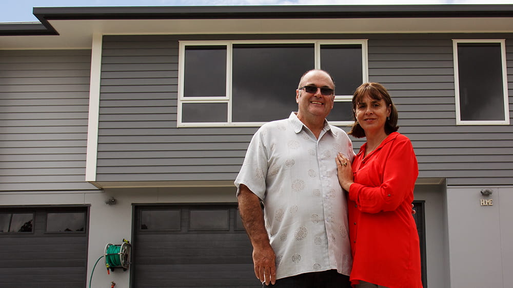 The OKanes in front of their rebuilt home powered by gas