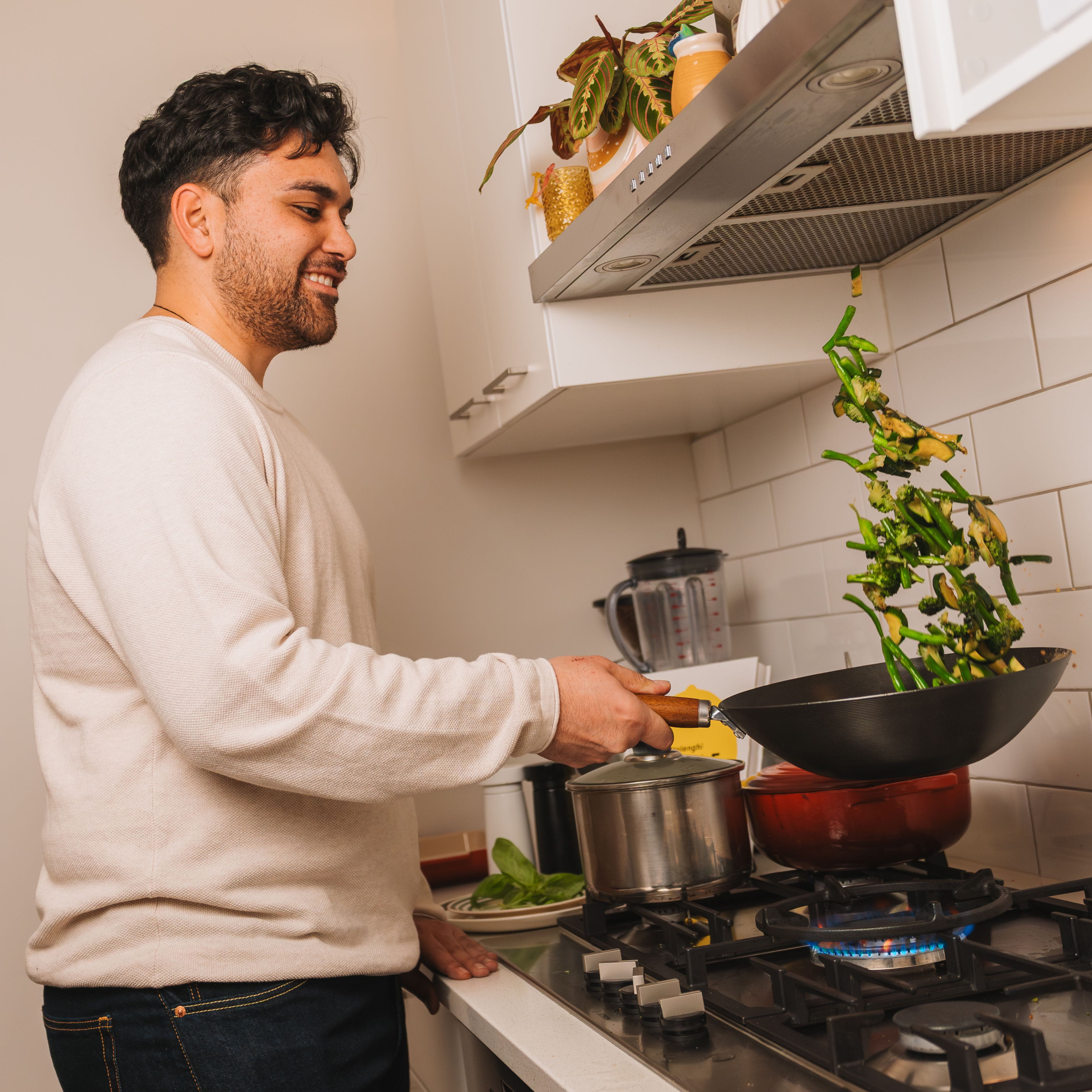 Man cooking a stir fry over gas in the kitchen.